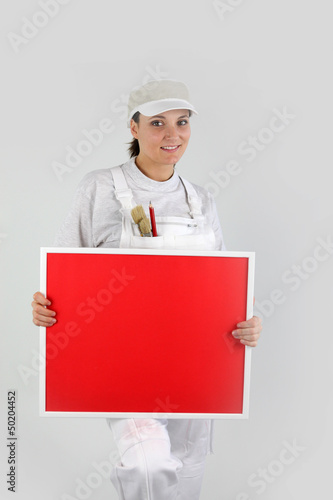 Photo: A woman painter holding up a red board A woman painter holding up a red board