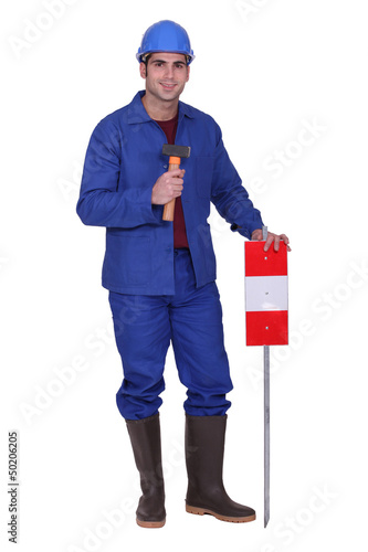 Photo: Construction worker standing with a mallet and traffic sign Construction worker standing with a mallet and traffic sign