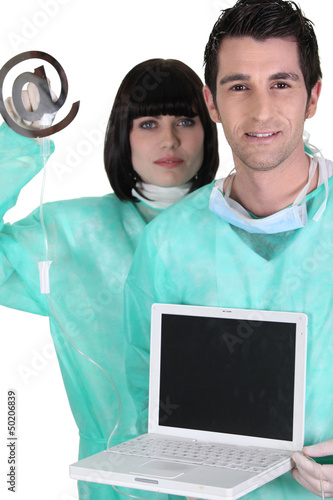 Photo: medical workers holding a laptop and an at sign medical workers holding a laptop and an at sign