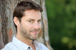 Portrait of man in front of tree trunk