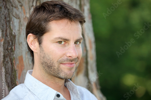 Photo: Portrait of man in front of tree trunk Portrait of man in front of tree trunk