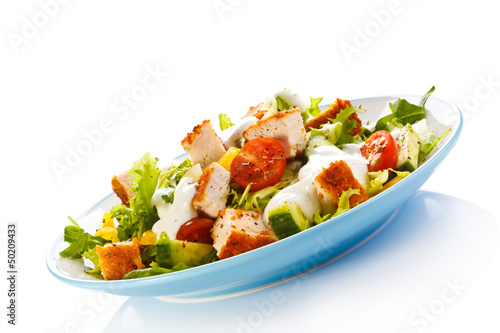 Photo: Fried chicken breast and vegetables on white background Fried chicken breast and vegetables on white background