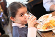 Little girl eating meal in restaurant