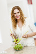 Photo: Smiling woman tossing salad in kitchen Smiling woman tossing salad in kitchen