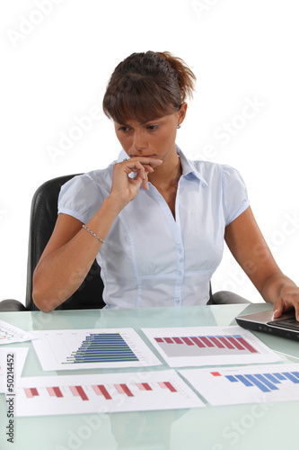 Photo: Concerned office worker working with bar charts Concerned office worker working with bar charts