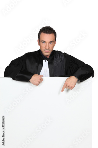 Photo: Man in black robes pointing at a board left blank for message Man in black robes pointing at a board left blank for message