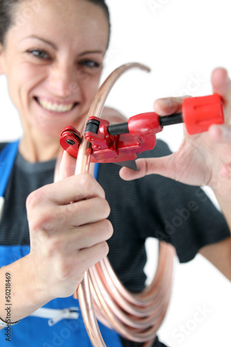 Photo: Female plumber cutting copper pipe Female plumber cutting copper pipe