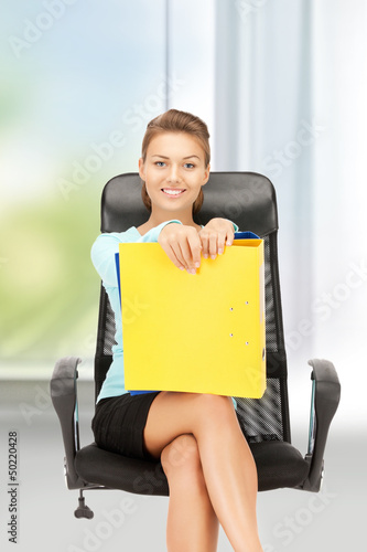 Photo: young businesswoman with folders sitting in chair young businesswoman with folders sitting in chair