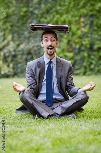 Photo: Young businessman meditating in the garden Young businessman meditating in the garden
