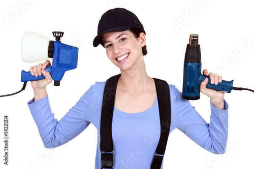 Photo: Woman holding paint sprayer and heat gun Woman holding paint sprayer and heat gun