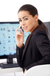 Photo: Business woman talking phone while sitting in front of computer Business woman talking phone while sitting in front of computer