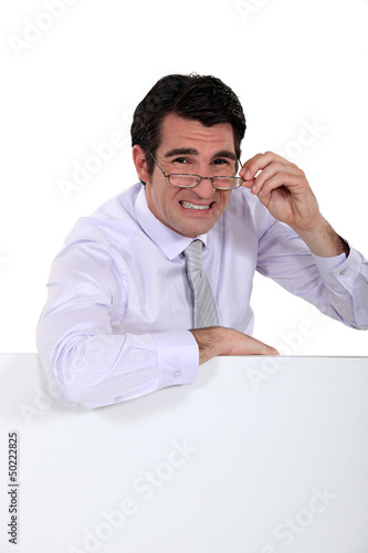 Photo: Doubtful man peering over his glasses Doubtful man peering over his glasses