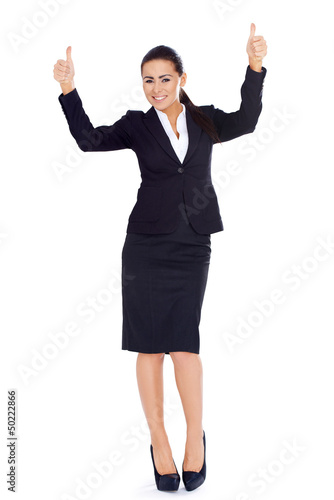 Photo: Business woman standing and showing thumbs up gesture Business woman standing and showing thumbs up gesture