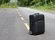 lone suitcase stands in the middle of the road