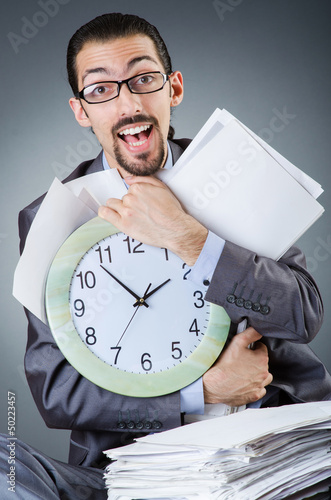 Photo: Man with clock and pile of papers Man with clock and pile of papers