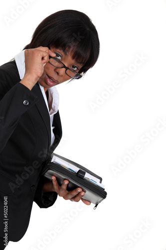 Photo: black businesswoman with lowered glasses holding agenda black businesswoman with lowered glasses holding agenda