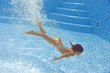 Underwater child in swimming pool, girl swims and having fun