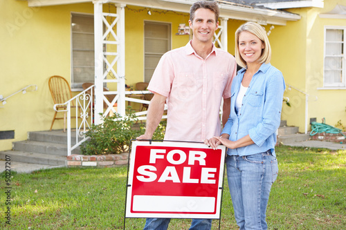 Photo: Couple Standing By For Sale Sign Outside Home Couple Standing By For Sale Sign Outside Home