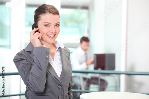 Photo: Young businesswoman making a call in the office Young businesswoman making a call in the office