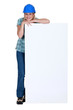 Woman with protective helmet leaning on a white sign