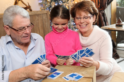 Photo: Little girl playing cards with her grandparents Little girl playing cards with her grandparents