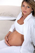 Pregnant blond woman sat on bed
