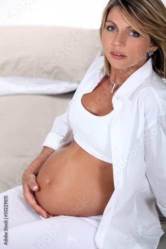 Photo: Pregnant blond woman sat on bed Pregnant blond woman sat on bed