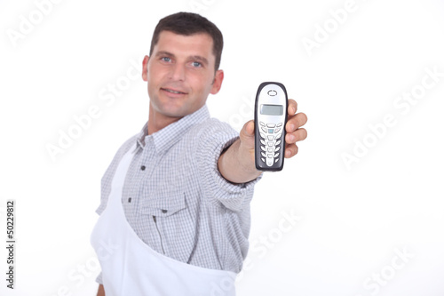 Photo: Dark haired man holding out mobile telephone Dark haired man holding out mobile telephone