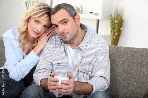 Photo: Couple sitting on sofa with a cup of coffee Couple sitting on sofa with a cup of coffee