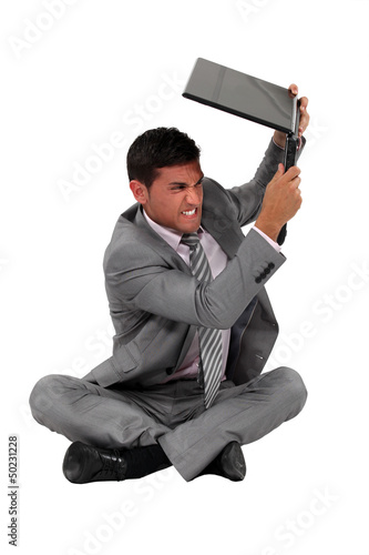 Photo: A businessman about to smash his laptop. A businessman about to smash his laptop.