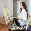 Female artist paints picture on canvas