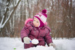Adorable girl dig snow with small shovel in park