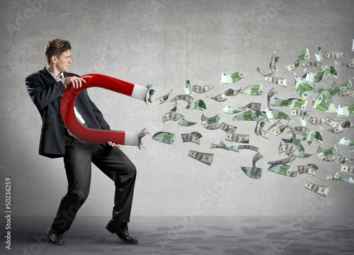 Photo: Businessman attracts money with a large magnet Businessman attracts money with a large magnet