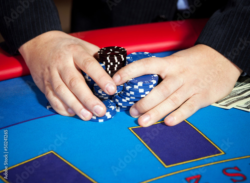 Photo: men's hand with chips, cards and dollars banknotes on table men's hand with chips, cards and dollars banknotes on table