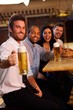 Happy man holding mug of beer in pub