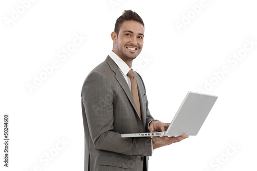 Photo: Young businessman using laptop smiling Young businessman using laptop smiling