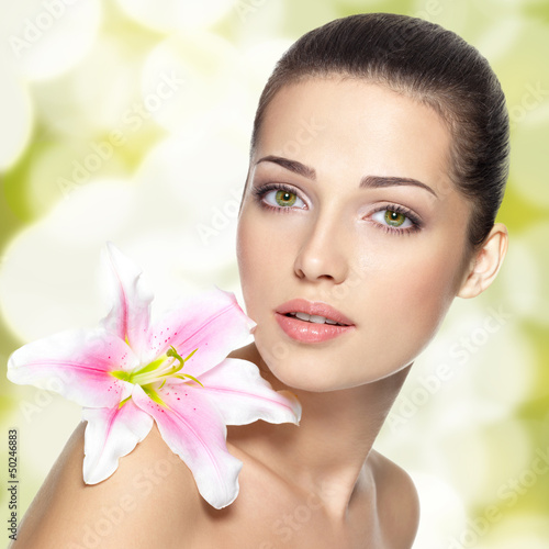 Photo: Beauty face of young woman with flower. Beauty treatment concept Beauty face of young woman with flower. Beauty treatment concept