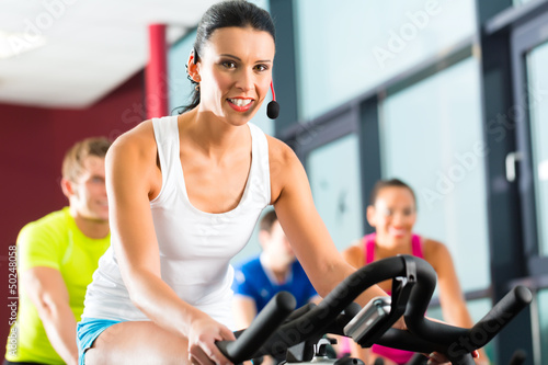 Photo: Group of people spinning on bikes in gym Group of people spinning on bikes in gym