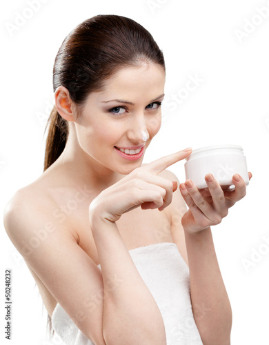 Photo: Woman putting on lifting cream from white container Woman putting on lifting cream from white container