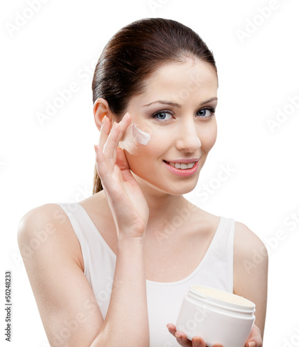 Photo: Woman applying moisture cream from container on face Woman applying moisture cream from container on face