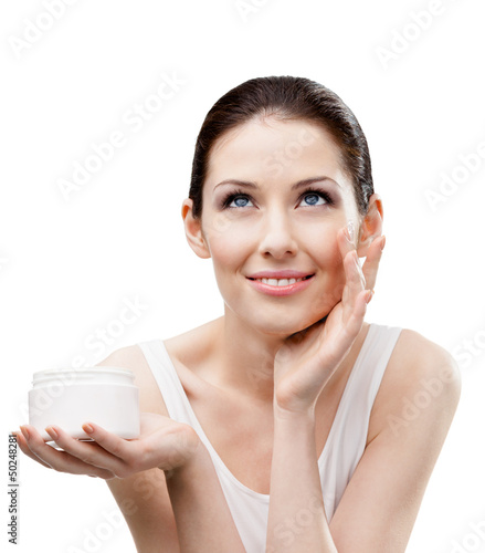 Photo: Woman putting on moisture cream from container on face Woman putting on moisture cream from container on face