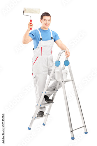 Photo: Full length portrait of a male painter holding a roller and stan Full length portrait of a male painter holding a roller and stan