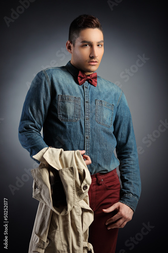 Photo: Handsome man wearing a bow tie and holding a coat Handsome man wearing a bow tie and holding a coat