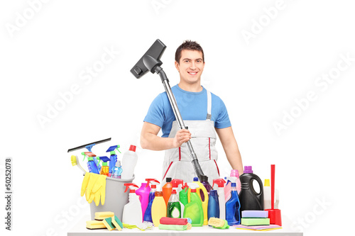 Photo: Male cleaner holding a hover and posing with cleaning supplies Male cleaner holding a hover and posing with cleaning supplies