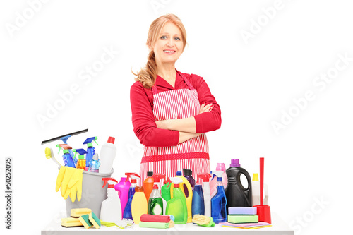 Photo: Smiling woman posing with cleaning supplies on a table Smiling woman posing with cleaning supplies on a table