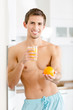 Half-naked man with glass of juice and orange