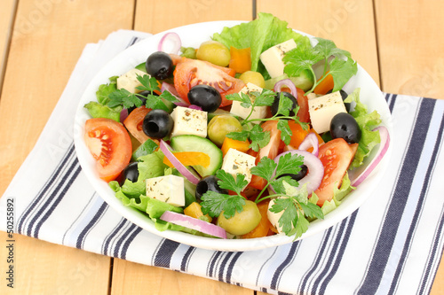 Photo: Fresh salad in plate on wooden table Fresh salad in plate on wooden table