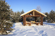 Wooden gazebo in the winter forest.