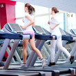 Photo: Two young sporty women run on machine Two young sporty women run on machine