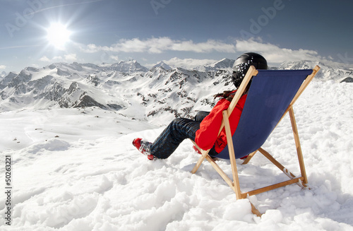Photo: Women at mountains in winter lies on sun-lounger Women at mountains in winter lies on sun-lounger
